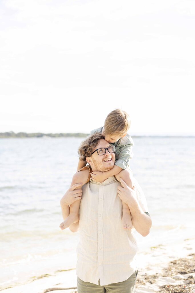 Photo of a a little boy on his dad's shoulder. The boy is kissing his dad's forehead | Sharon Joseph Photography | Brisbane Family Photographer