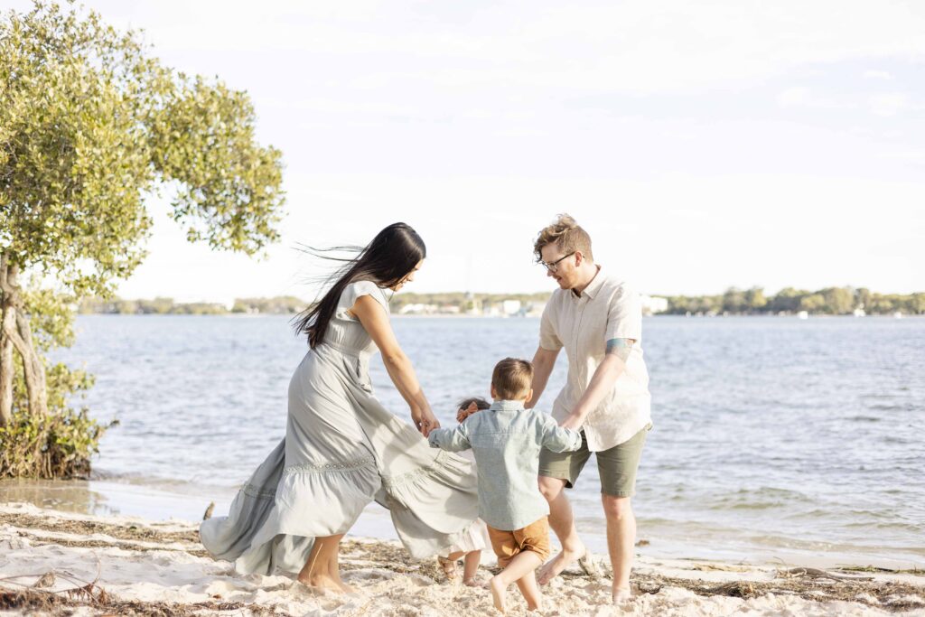 A family playing Ring around the Rosie on the beach | Sharon Joseph Photography | Fun family photos in Brisbane