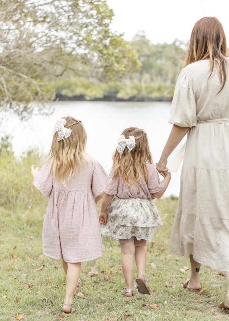 Mum and two girls walk towards the riverbank. Brisbane Family Photography by Sharon Joseph