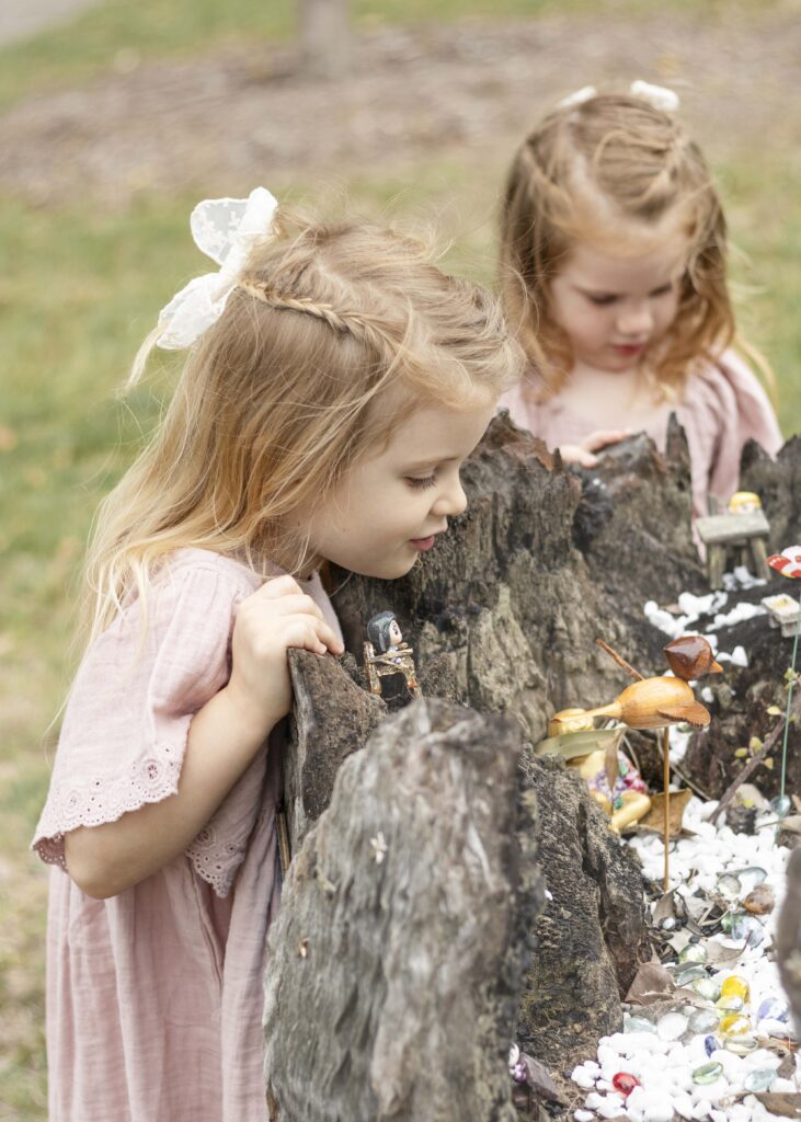 Little girls admiring a fairy garden. 