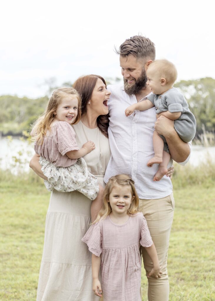 Family photo of family of five, parents, two girls and a baby boy. Family of five enjoying a family cuddle. Brisbane Family Photography by Sharon Joseph