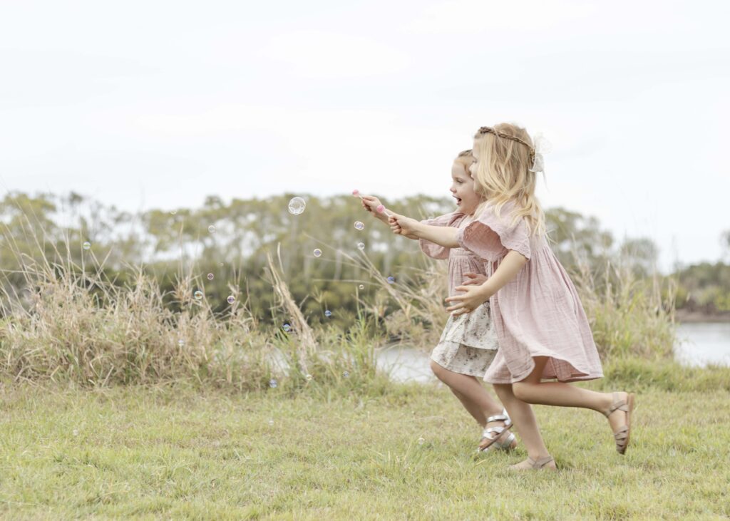 two little girls happily chasing bubbles. Brisbane Family Photography by Sharon Joseph