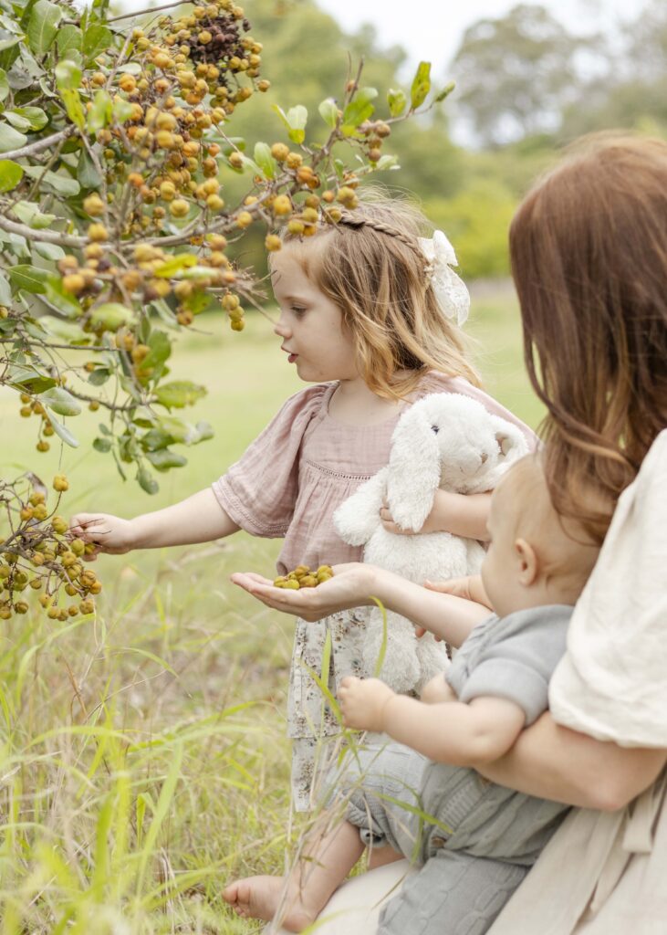 A little girl holding her bunny and picking pumpkins, as mum and little brother watch on. 
