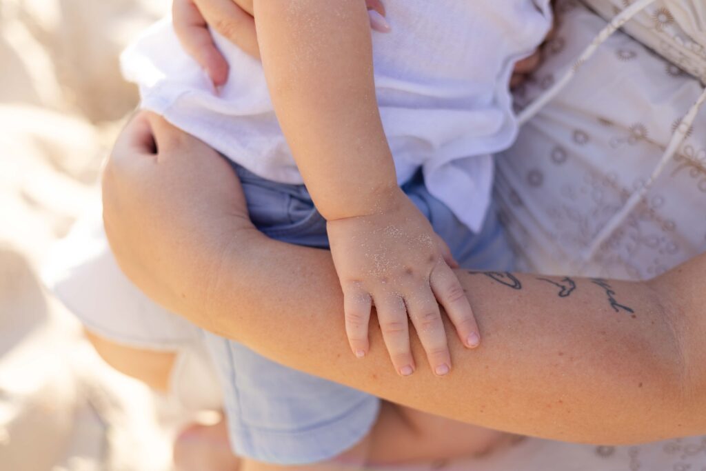 Sandy little hand of boy. He is holding his mother's arm.