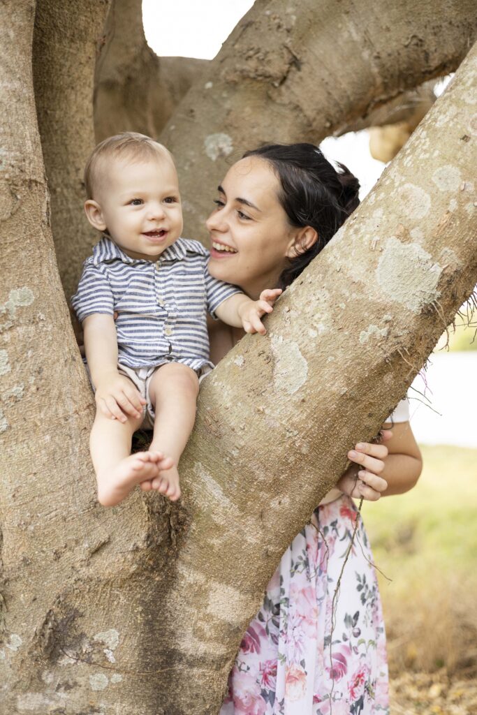 Baby  boy on tree with his mum holding him.