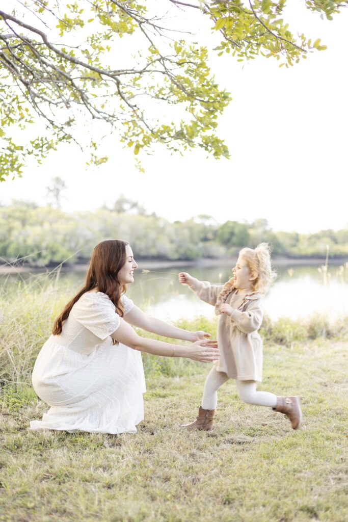 a little girl running to her mother's arms with a "ticklestick" grass