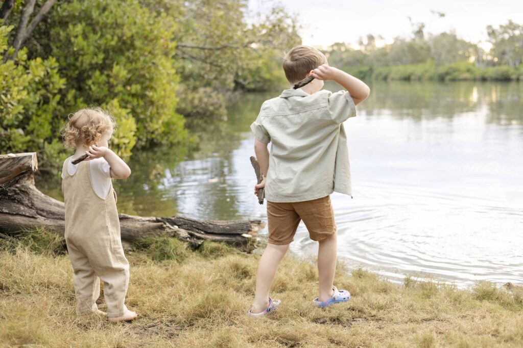 Boys throwing bark in river.