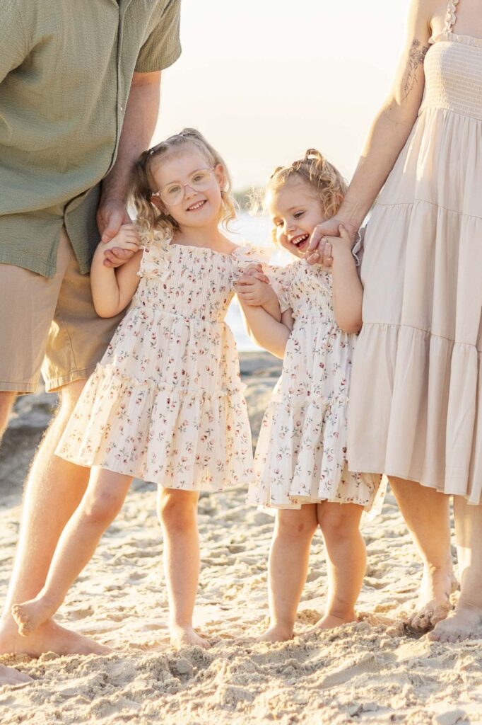 Happy sisters holding hands with their parents, at their family photoshoot in North Brisbane
