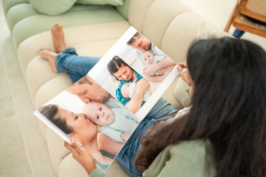 Lady holding photo album with photos of mum, dad and newborn baby boy, taken at their outdoor newborn photo session in North brisbane