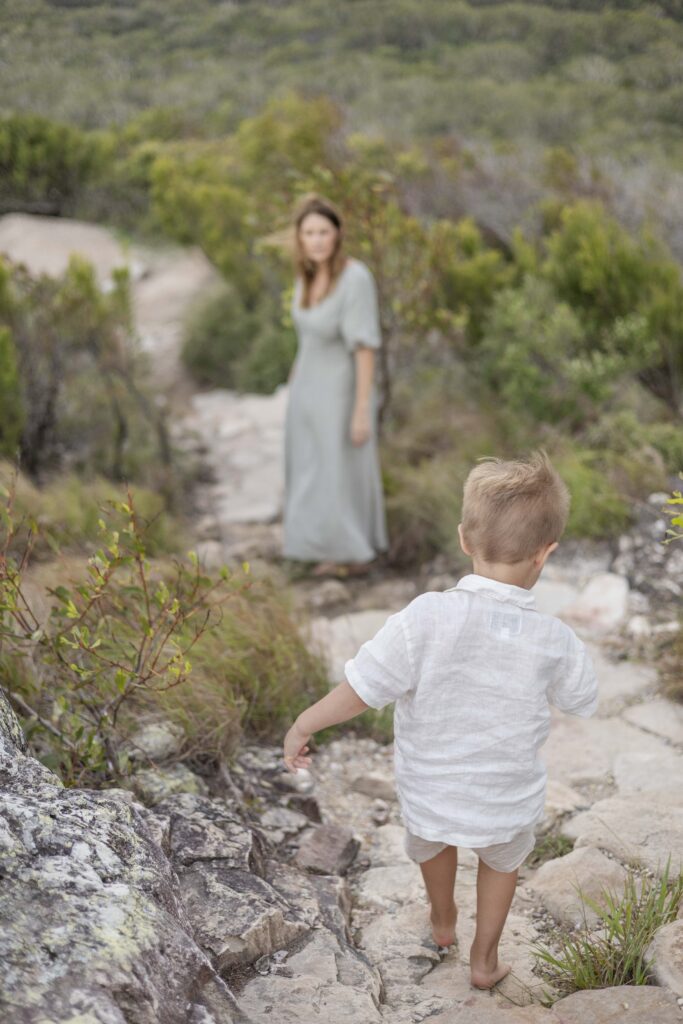 A little boy climbs down a hill on a kid friendly walking trail, about an hour from Brisbane.