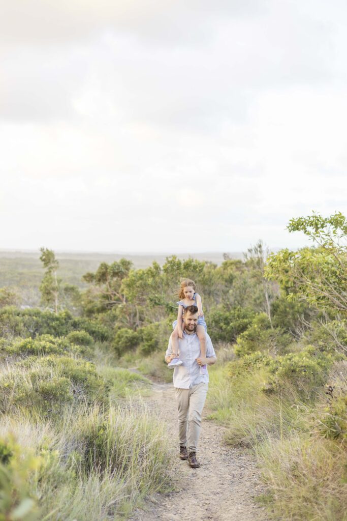 Dad carrying his young daughter on his shoulders as they walk up Emu Mountain. A family friendly outdoor activity near Brisbane.