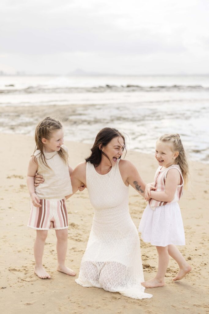 Happy moment between mum and her two little girls at their family photoshoot at Point Cartwright on Sunshine Coast