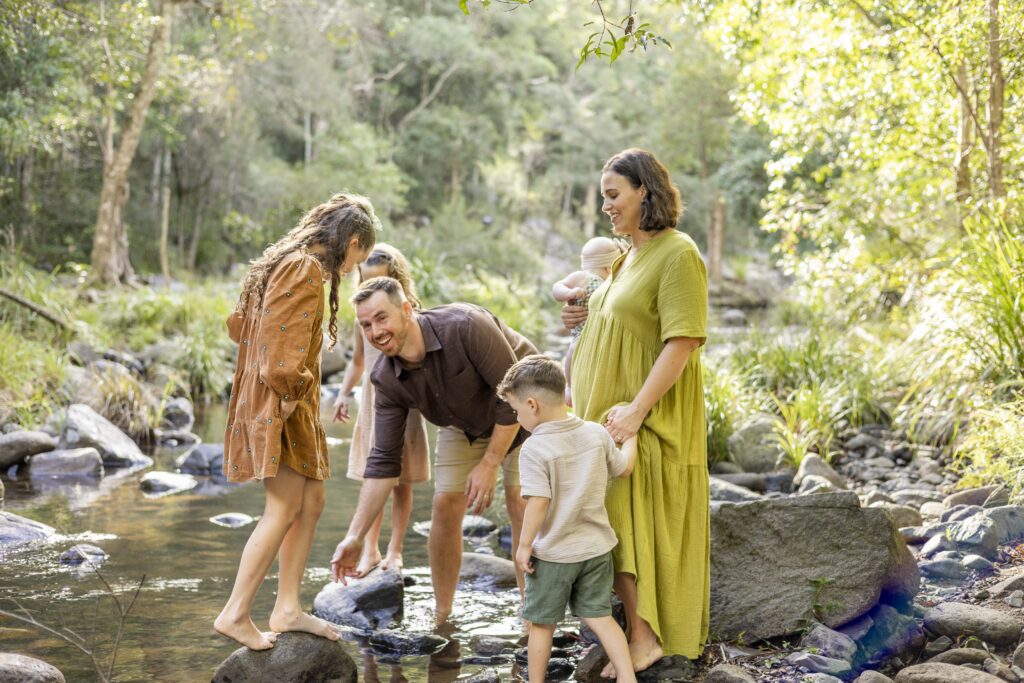 Family with colourful photoshoot outfit having fun at a creek near Brisbane. What to wear for family photos: Why neutral colours aren't your only option.
