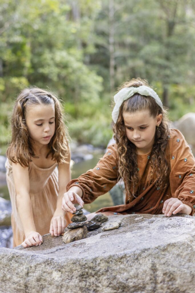Two sisters building a rock tower, during their family photography session at Cedar Creek