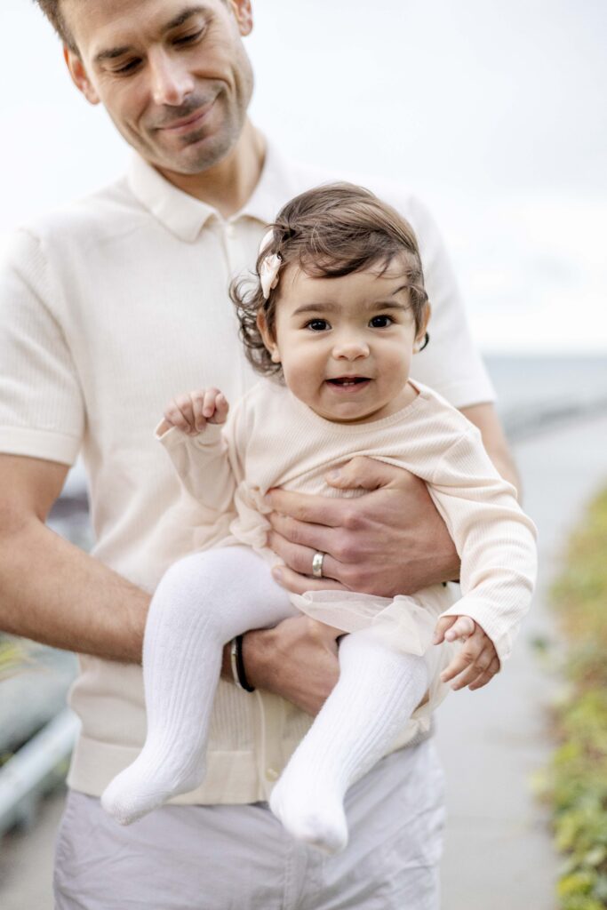 Dad holding smiling baby daughter, at their candid photography session in North Brisbane.