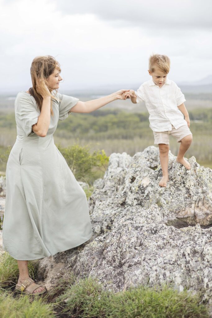 Mum helping little boy climb down a rock at Emu Mountain on Sunshine Coast. Natural family photography in Brisbane Northside/Moreton Bay. Sharon Joseph Photography