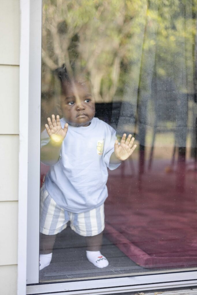 Baby boy looking out the window at in-home family photoshoot in Moreton Bay