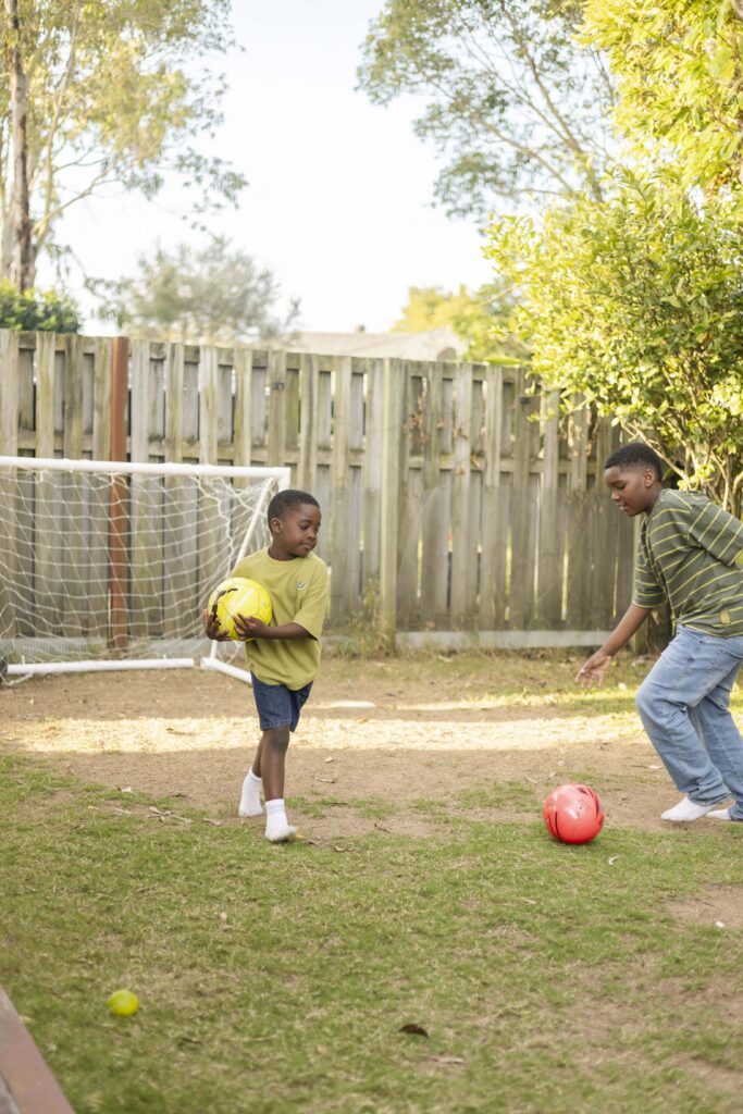 Brothers playing soccer in backyard